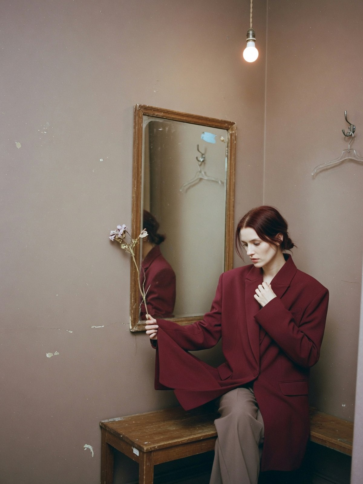 Femme assise en cabine d'essayage testant la tenue d'un blazer souple bordeaux en position assise.