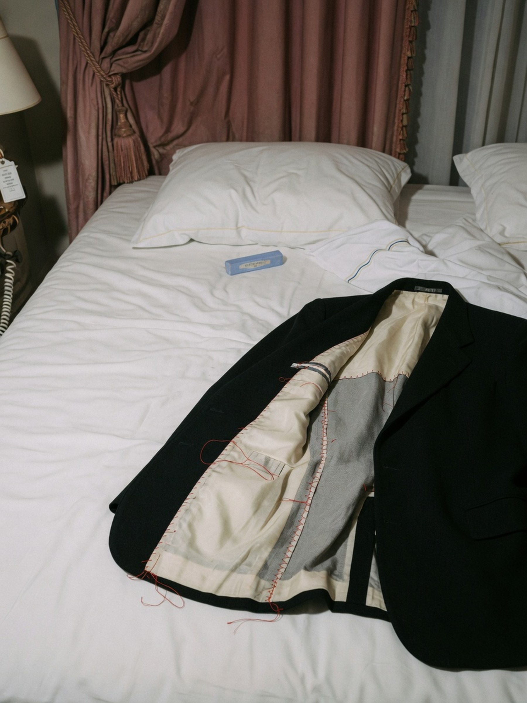 Blazer noir posé à plat, doublure entrouverte laissant voir la toile d'entoilage grise à l'intérieur