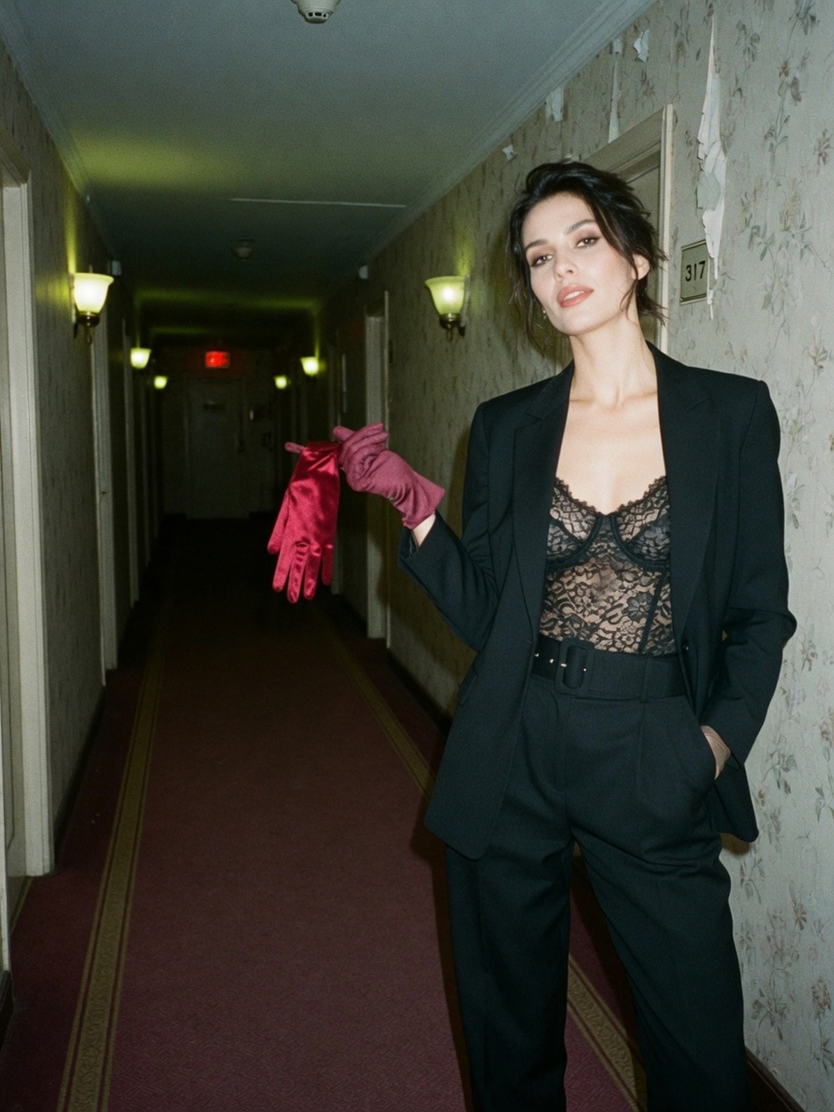 Mannequin dans un couloir portant un body en dentelle noire visible sous un blazer ouvert et un pantalon taille haute
