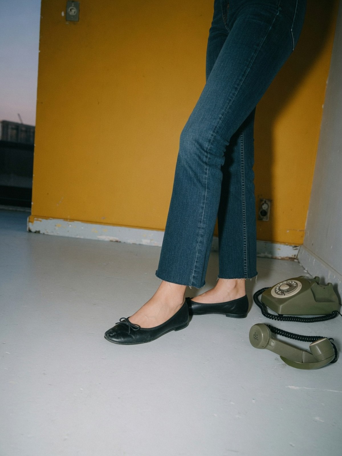 Gros plan sur un ourlet court de jean bootcut slim porté avec des ballerines plates à bout couvert.