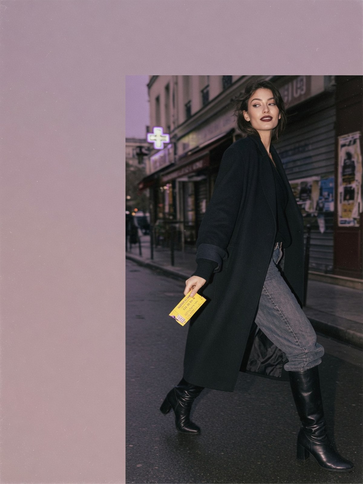 Mannequin dans la rue au crépuscule portant un jean glissé dans une botte cavalière noire sous un manteau long oversize