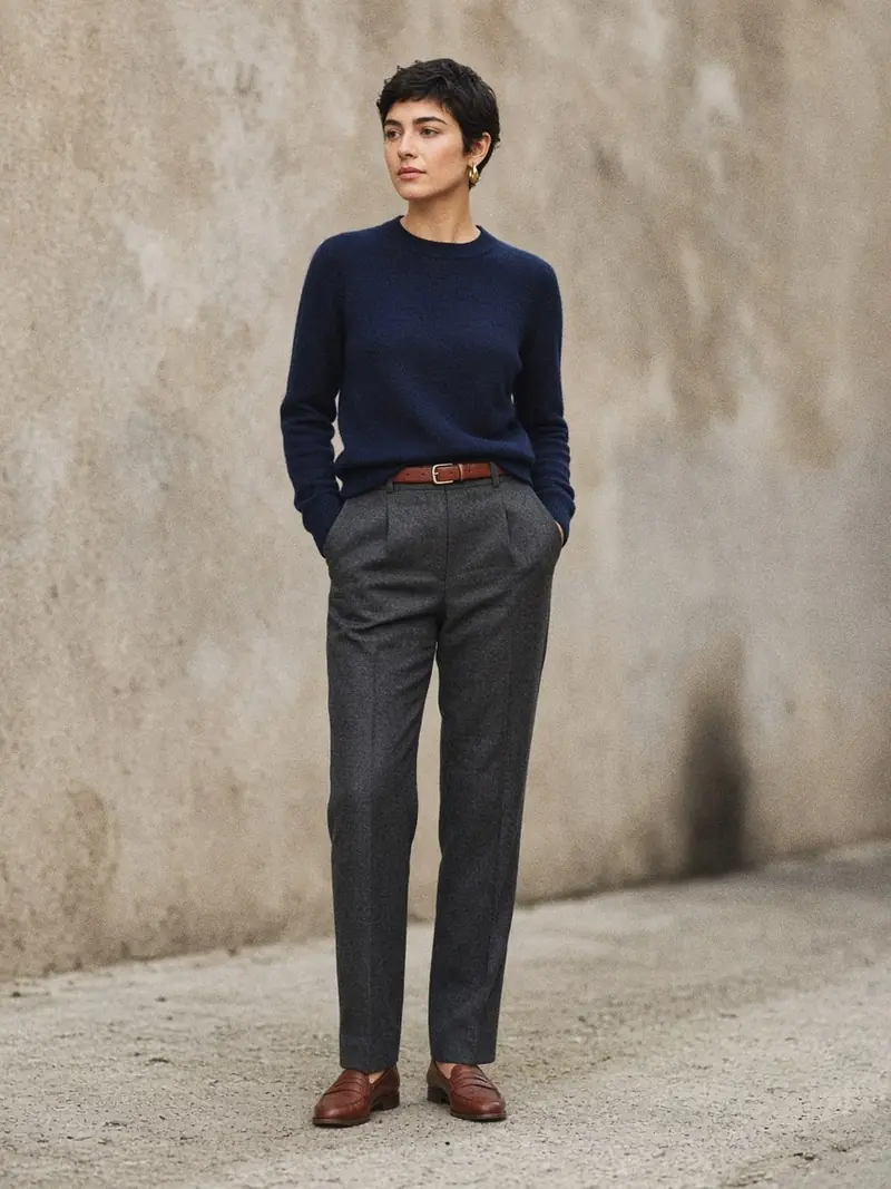 Illustration, mannequin fictif : Femme en pull fin bleu marine rentré dans un pantalon droit gris anthracite, ceinture et mocassins marron.