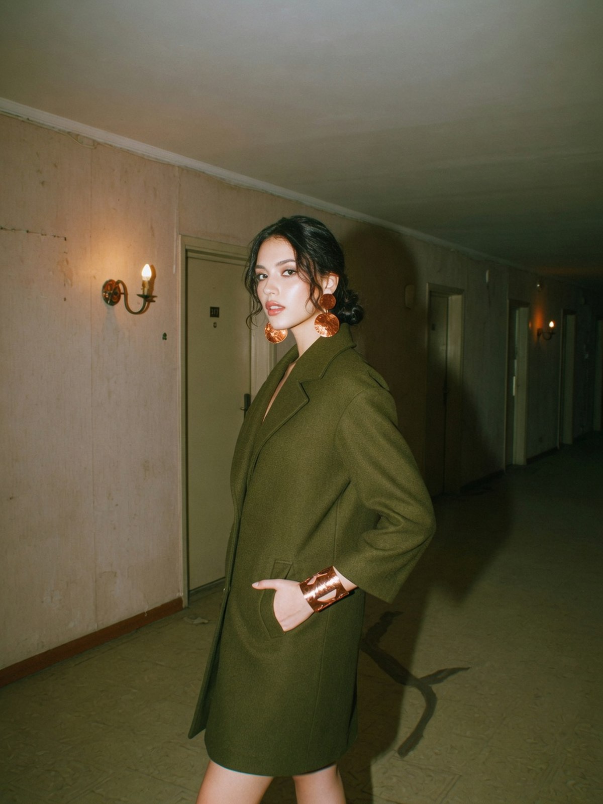 Mannequin en manteau olive avec bijoux en cuivre, association pièce forte et bijou pour la saison automne en colorimétrie