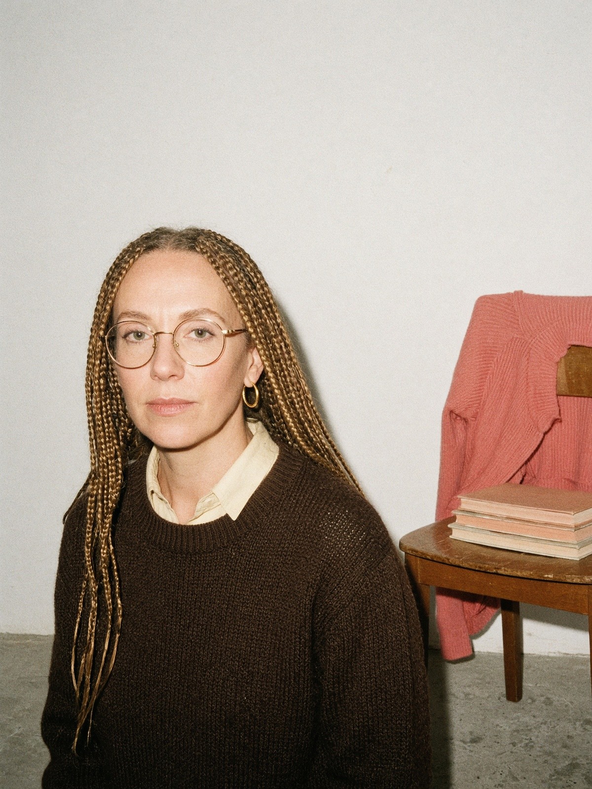 Mannequin en pull brun foncé avec col de chemise vanille par-dessus, créoles et lunettes en métal doré clair