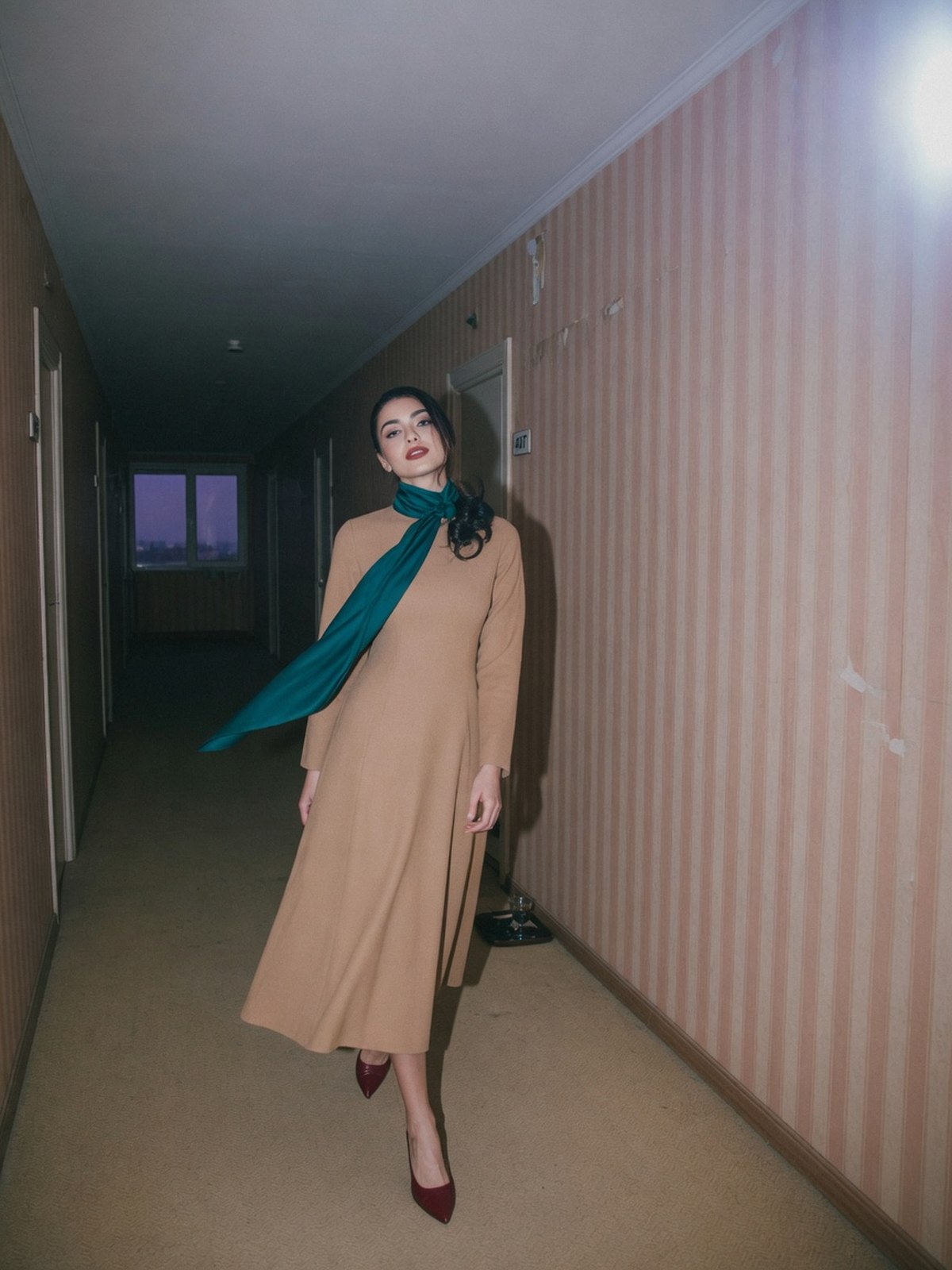 Robe longue camel accessoirisée d'un foulard bleu canard et de chaussures bordeaux.