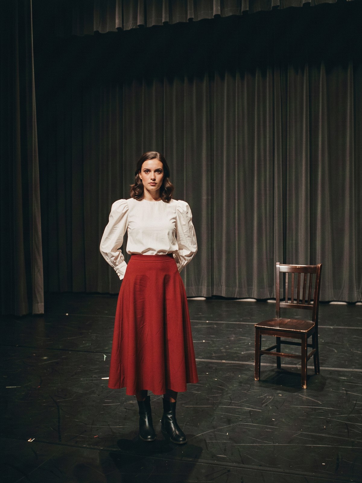 Mannequin en blouse blanche à manches bouffantes et longue jupe rouge sur une scène de théâtre