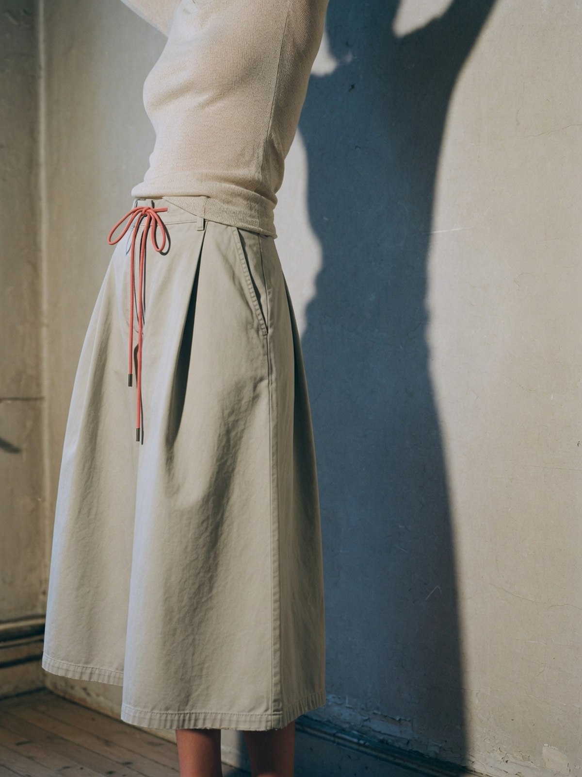Culotte-jupe en toile de coton à taille froncée portée avec un pull fin, cadrage à hauteur de taille
