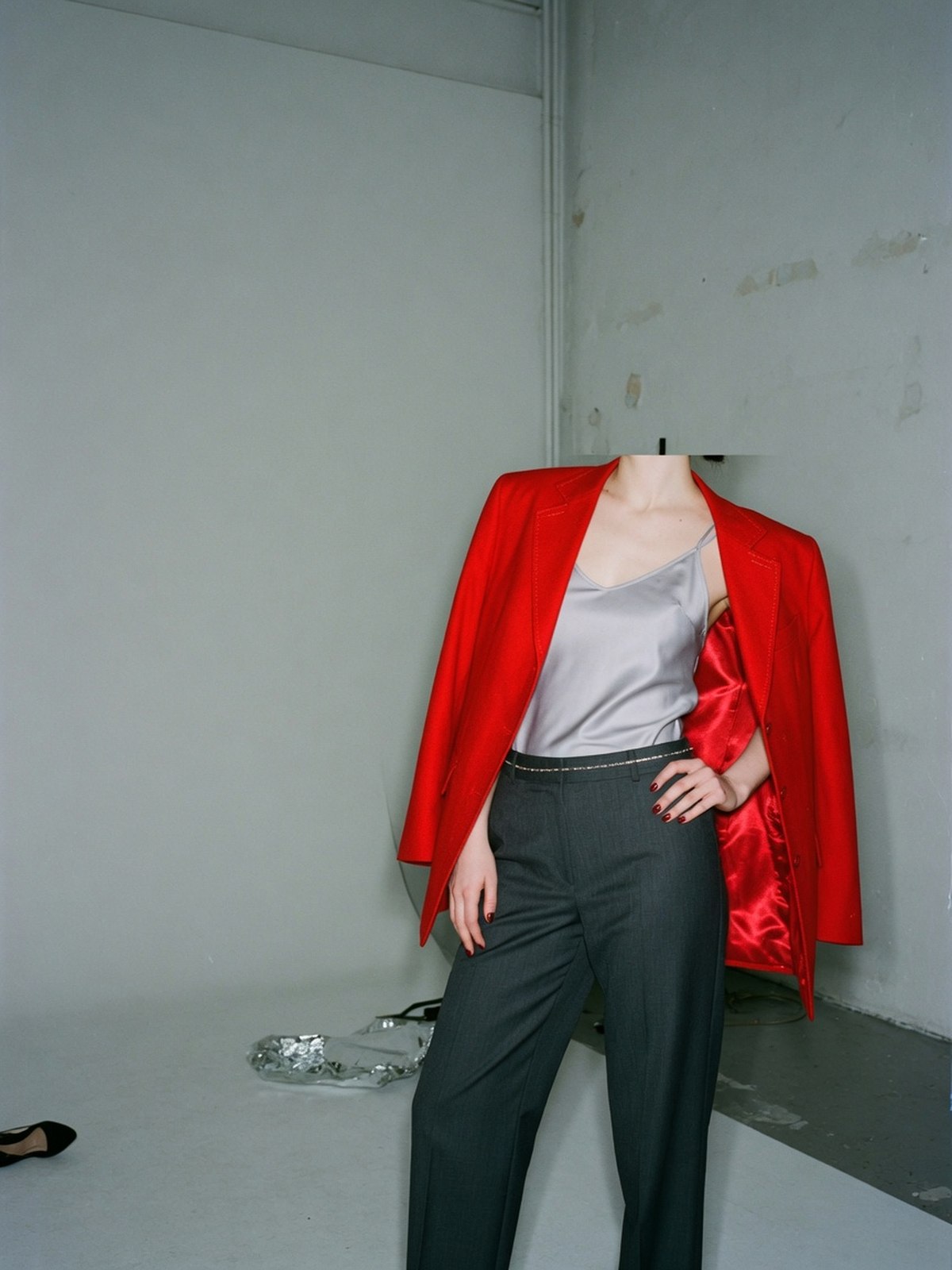 Blouson de survêtement oversize rouge porté ouvert sur un caraco en soie et un pantalon droit