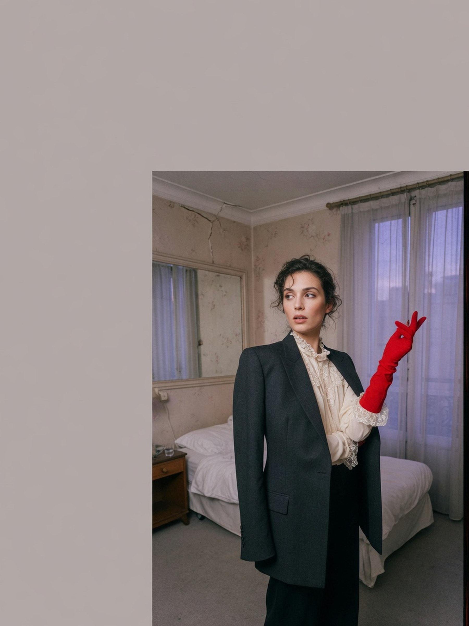 Mannequin en veste structurée dans une chambre d'hôtel, lumière de fin de journée, accessoire rouge inattendu