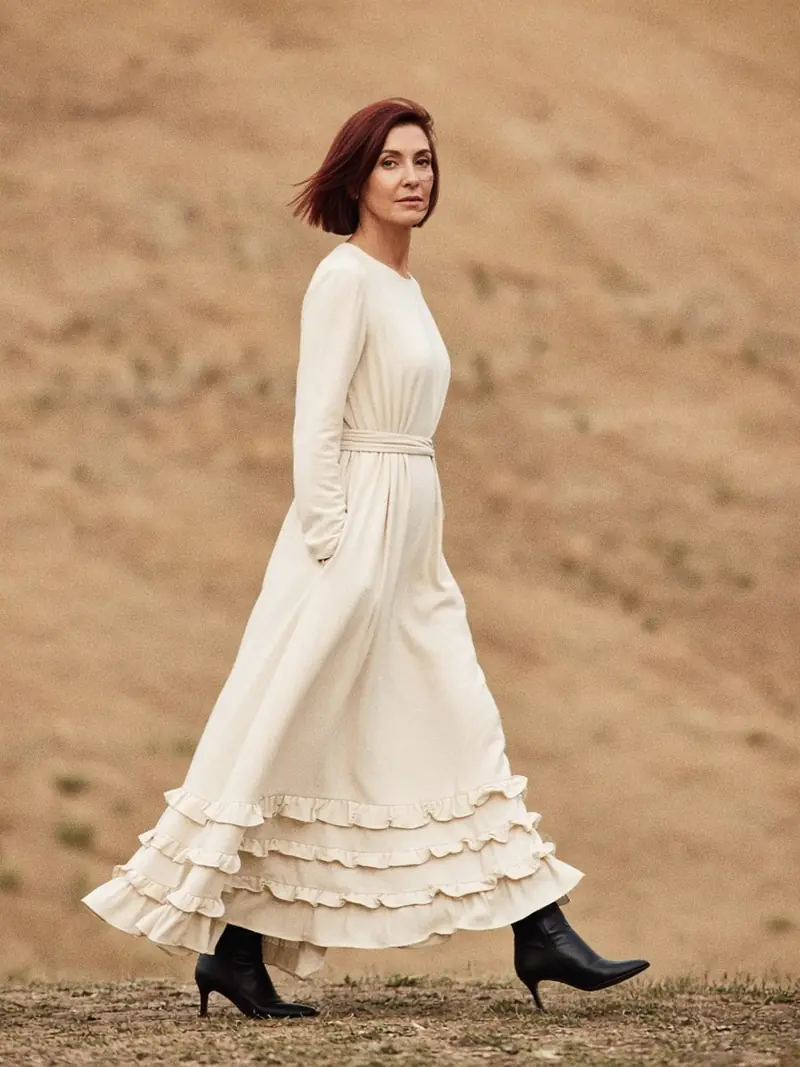 Illustration, mannequin fictif : Femme de pied en pied portant une robe midi crème à volants superposés sur l'ourlet, ceinturée à la taille, avec des bottines noires pointues.