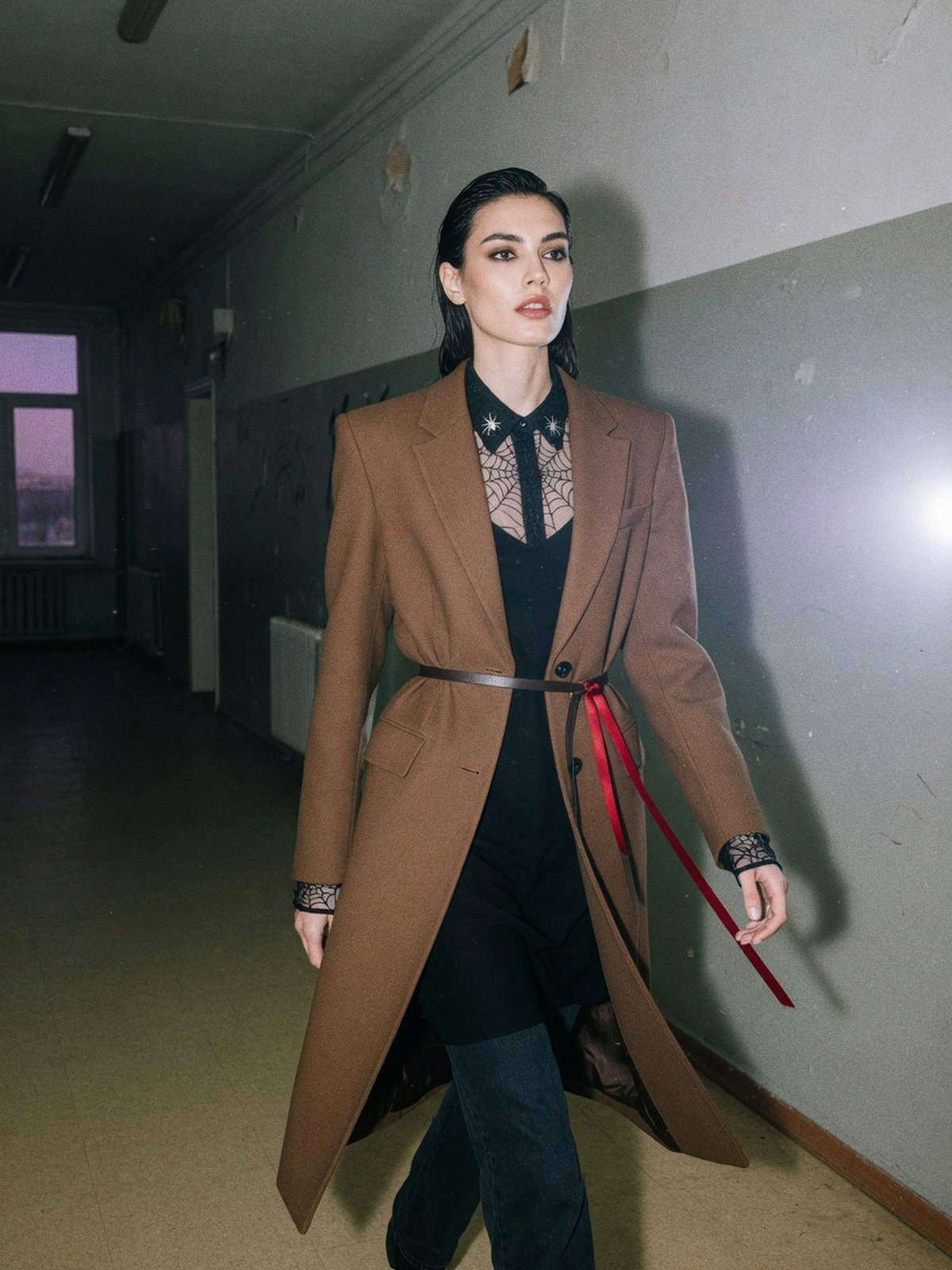 Mannequin dans une rue au crépuscule, portant un jean et un haut noir uni sous une blouse transparente à motif toile d'araignée, seule pièce forte de la tenue.