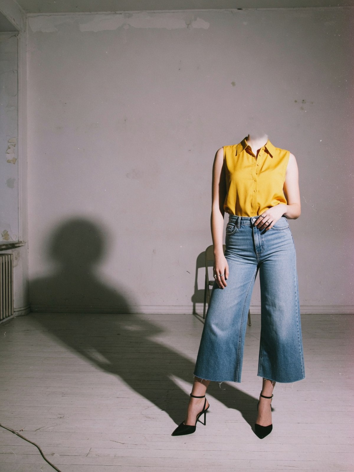 Une silhouette portant un jean large taille haute, ourlet arrêté à la cheville, associé à des talons pointus, dans un studio épuré.
