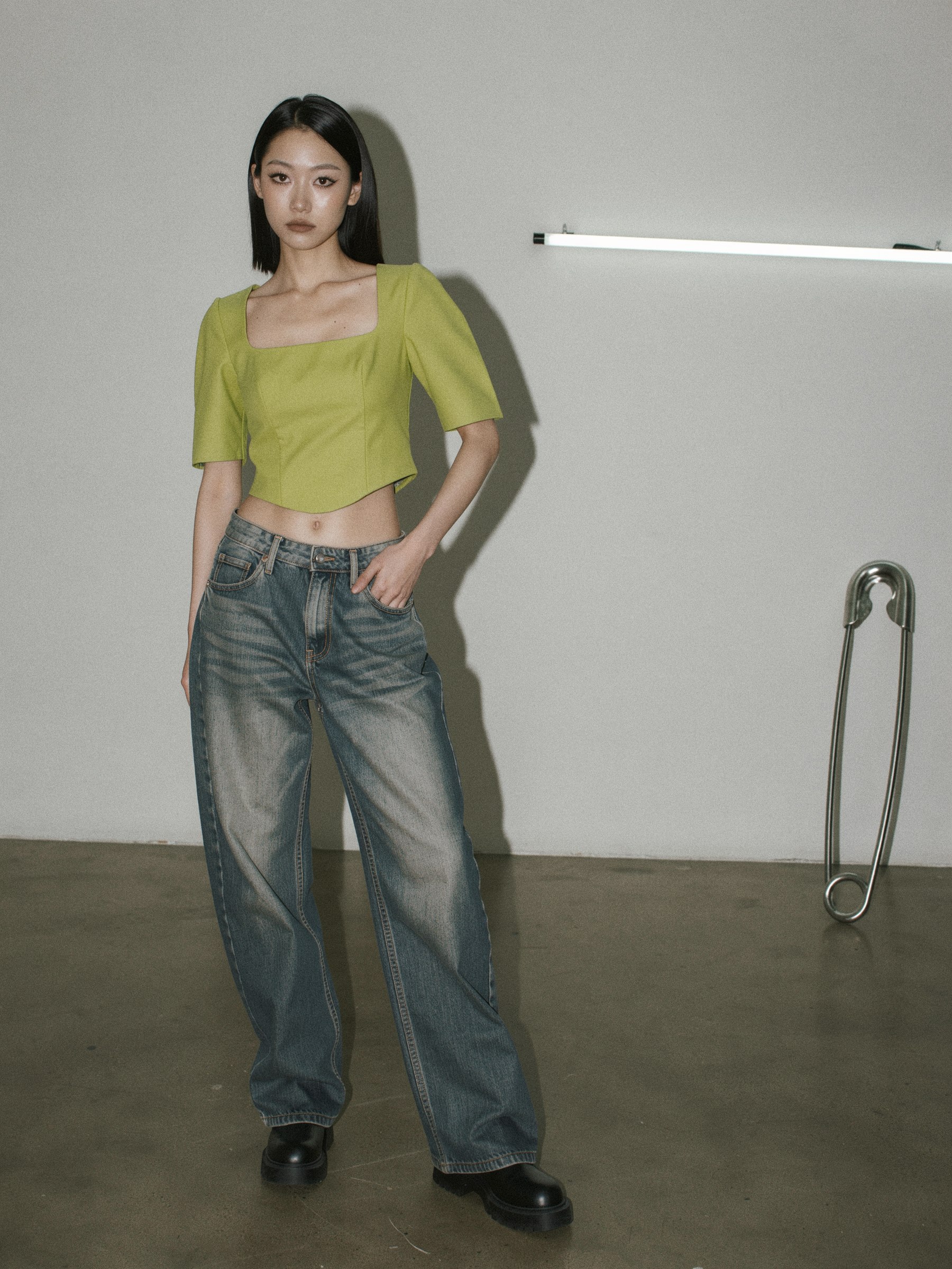 Mannequin de mode portant un jean baggy taille basse ample, lumière flash directe, décor minimal.
