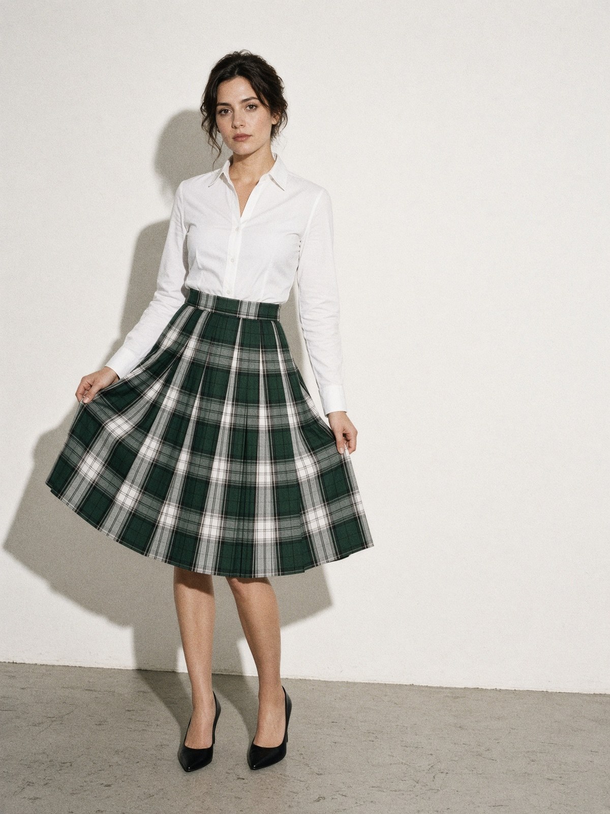 Mannequin ouvrant un pli d'une jupe tartan vert, blanc et noir pour montrer l'intérieur du pli