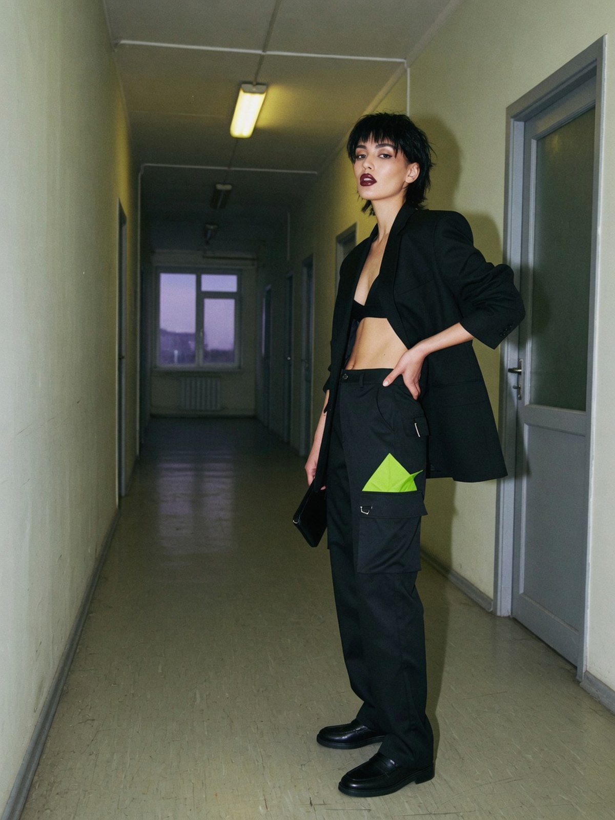 Mannequin en pantalon cargo noir taille haute, blazer structuré et mocassins, dans un couloir de bureau.