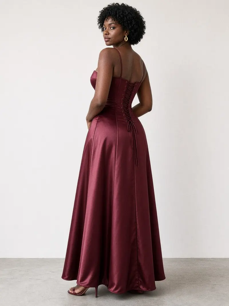 Illustration, mannequin fictif : Mannequin de dos en robe longue en satin bordeaux à buste baleiné fermé par un laçage à œillets sur un panneau large.