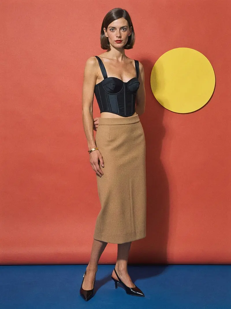 Illustration, mannequin fictif : Femme en bustier noir baleiné court porté avec une jupe crayon midi camel taille haute et des escarpins noirs.